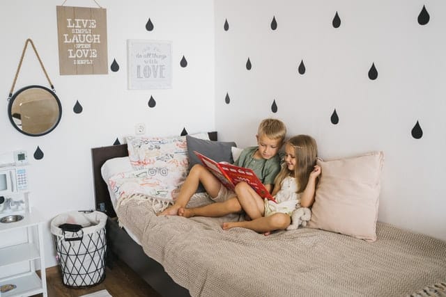 Two kids reading a book in a bed